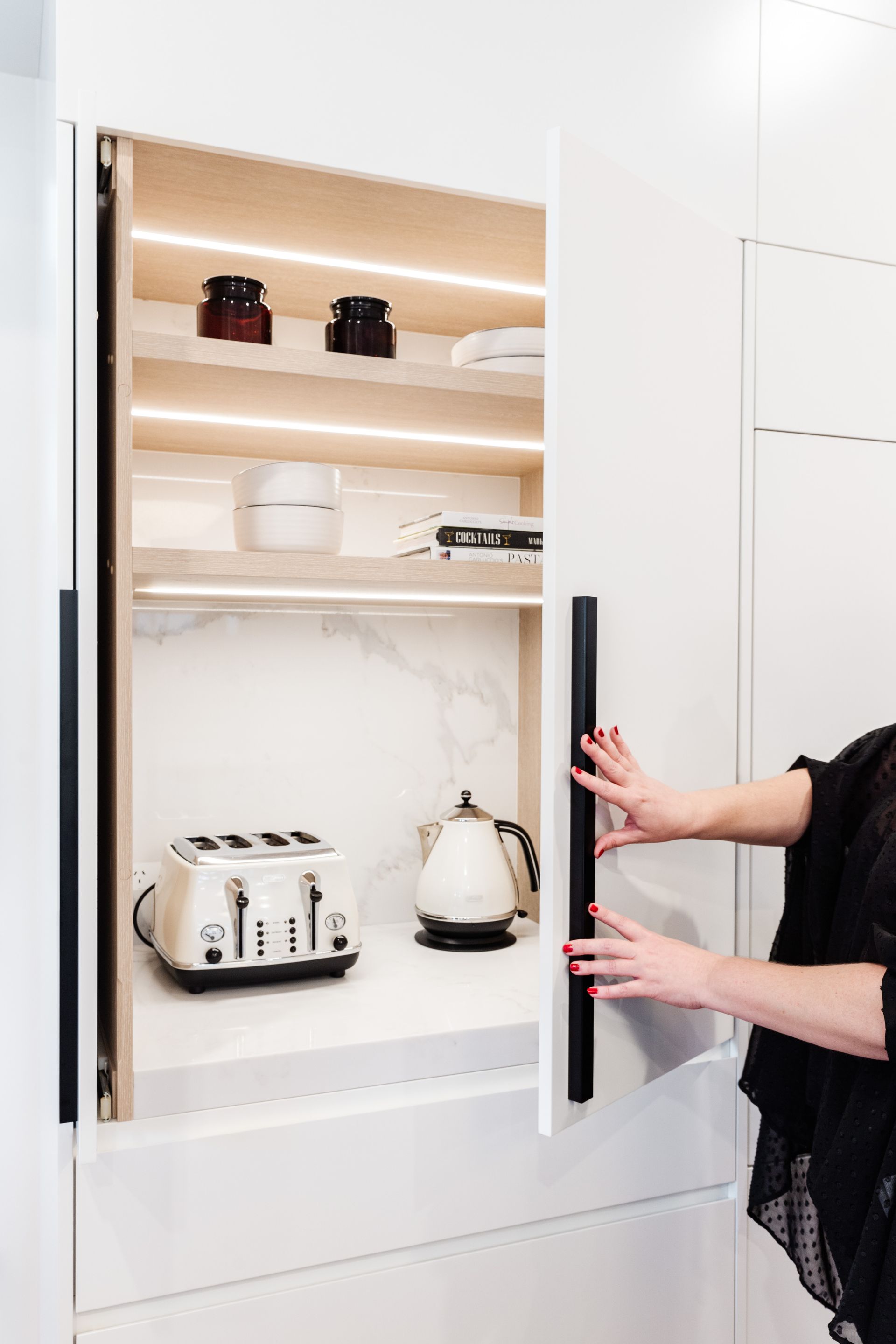 Person Opening a White Kitchen Cabinet — PKJ Design in Unanderra, NSW