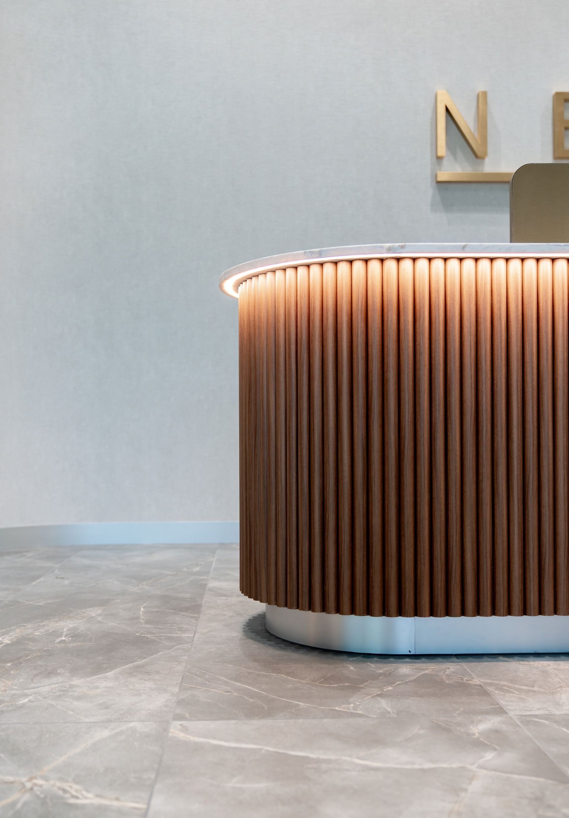 Reception Desk With Vertical Wood Slats and Warm Lighting — PKJ Design in Unanderra, NSW