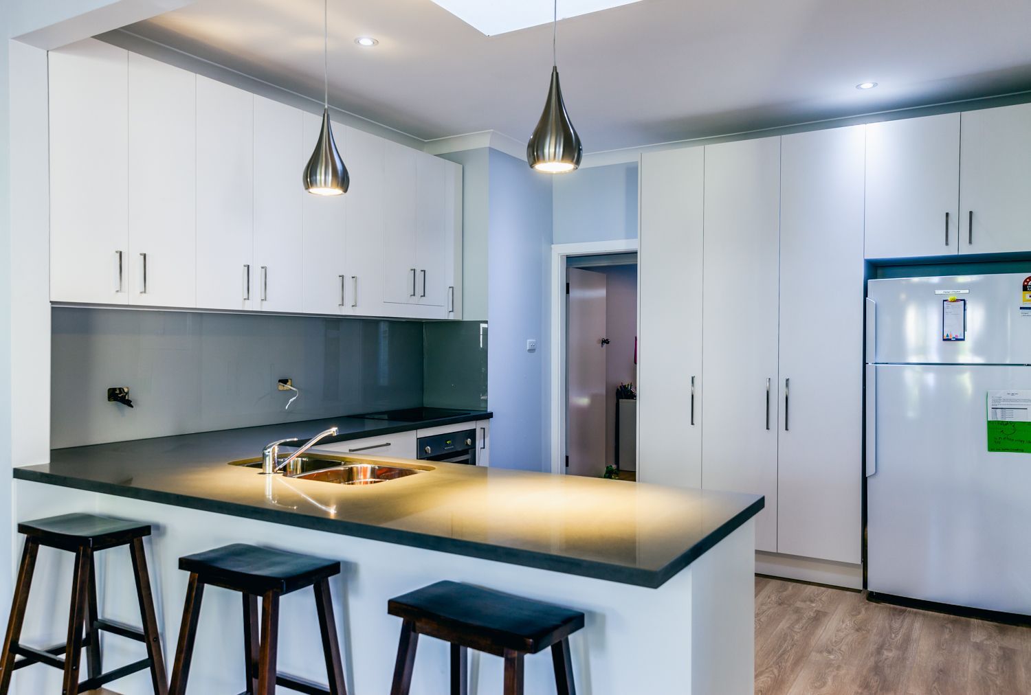 Modern White Kitchen With Island, Black Stools — PKJ Design in Unanderra, NSW