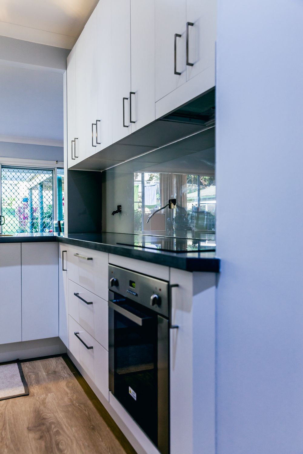 Kitchen With Cabinets, Built-in Oven, and Glass Backsplash — PKJ Design in Unanderra, NSW