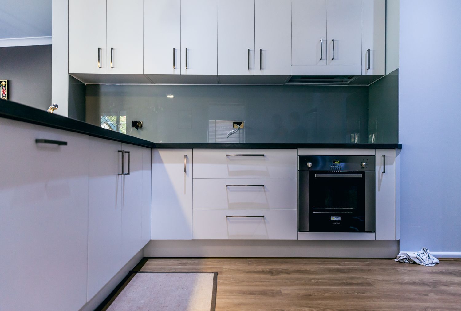 Modern Kitchen With White Cabinets and Black Countertop — PKJ Design in Unanderra, NSW