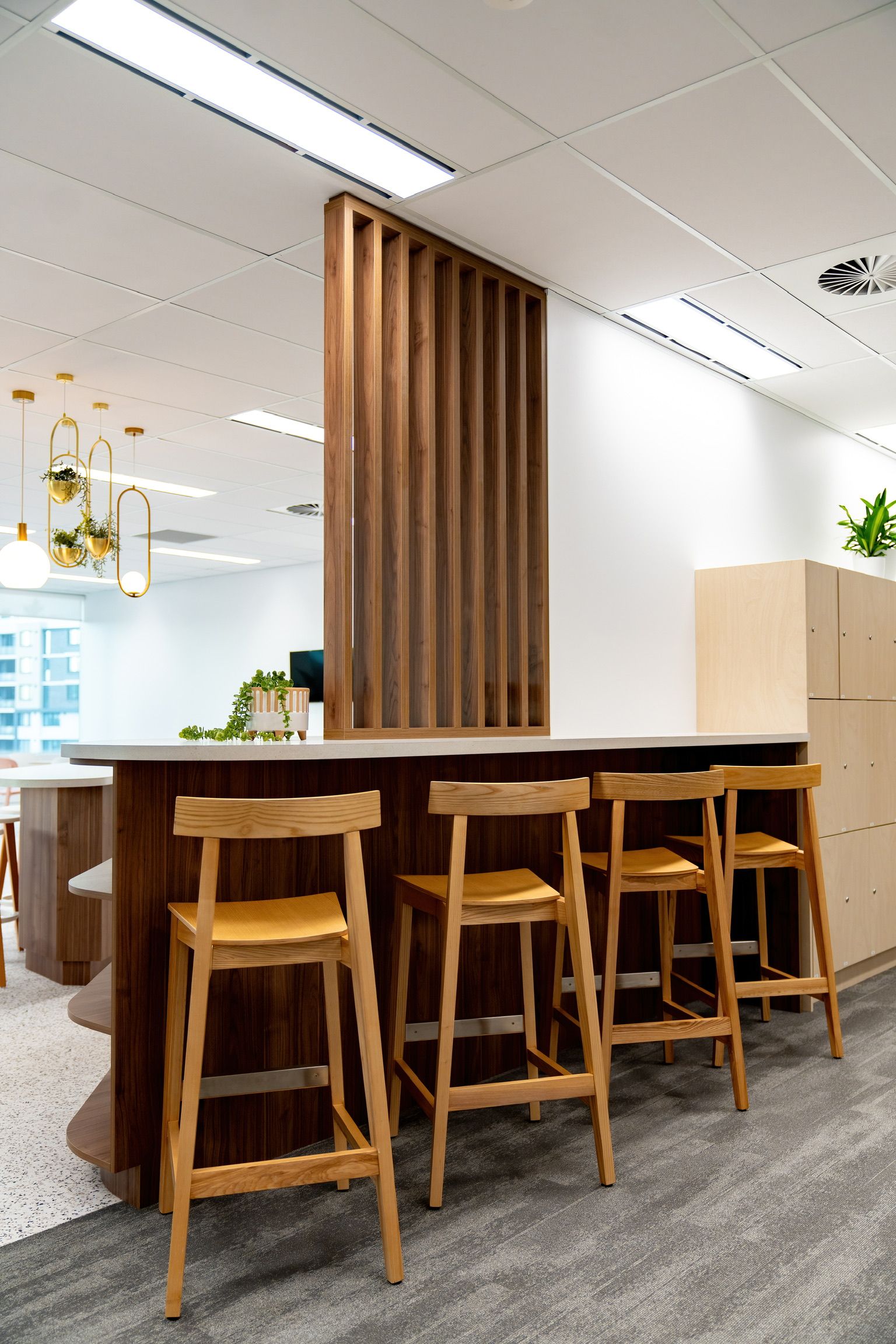 Modern Office Break Area With Wooden Stools at a High Table — PKJ Design in Unanderra, NSW