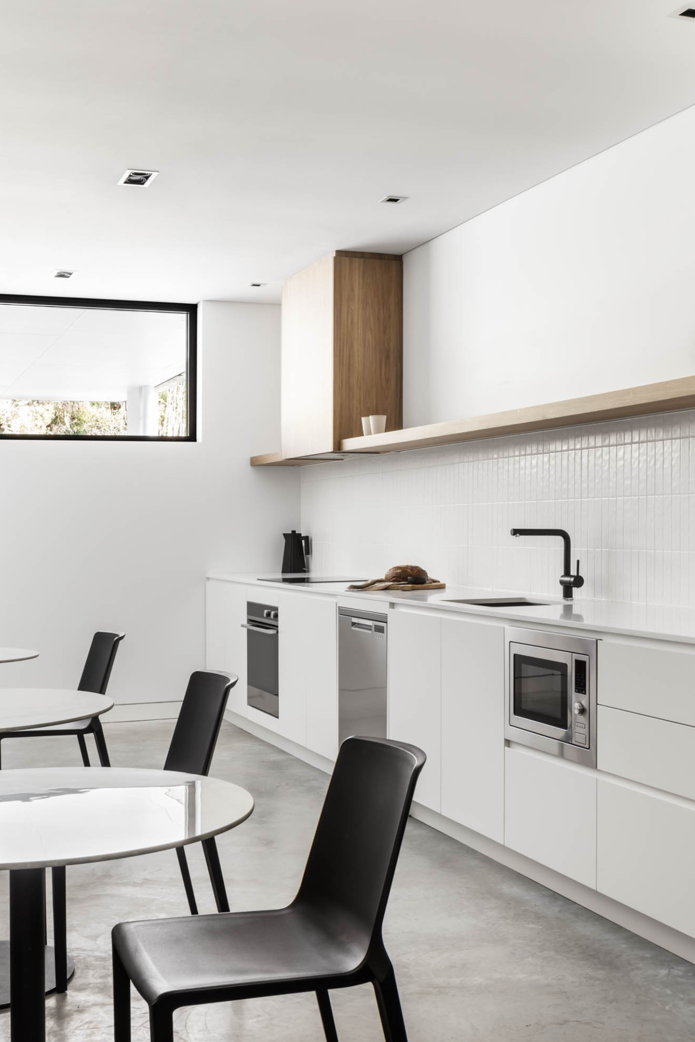 Modern White Kitchen With Black Chairs — PKJ Design in Unanderra, NSW