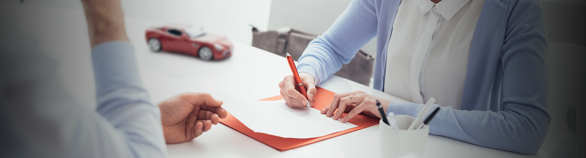Um homem e uma mulher estão sentados à mesa assinando um documento.