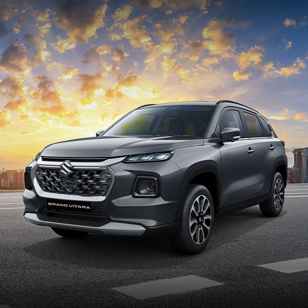 Um SUV cinza está estacionado na beira da estrada ao pôr do sol.