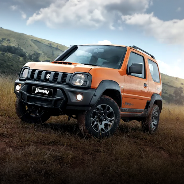 Um suzuki jimny laranja está estacionado em um campo gramado