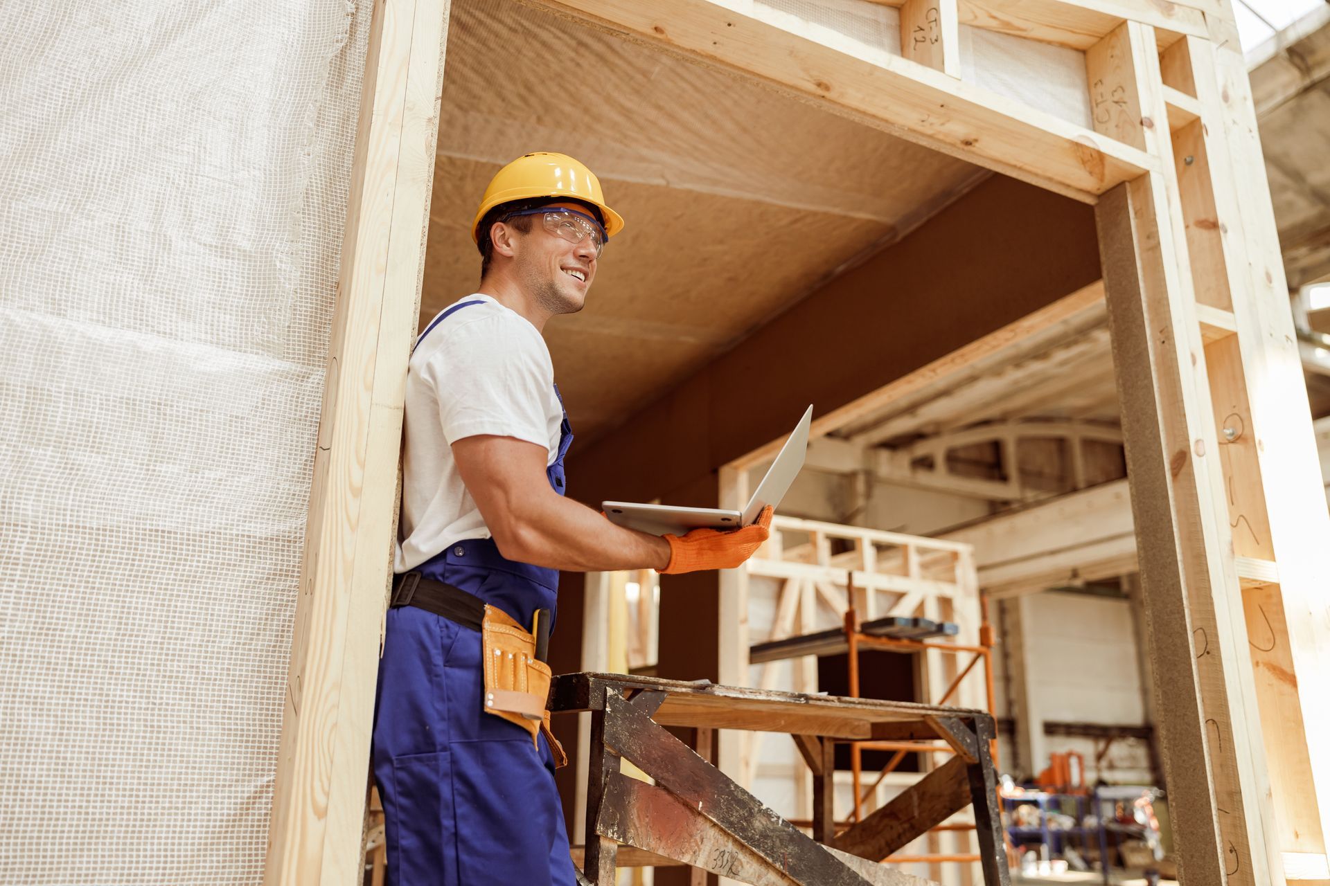 Construction worker in a yellow hard hat standing on scaffolding inside a building under construction