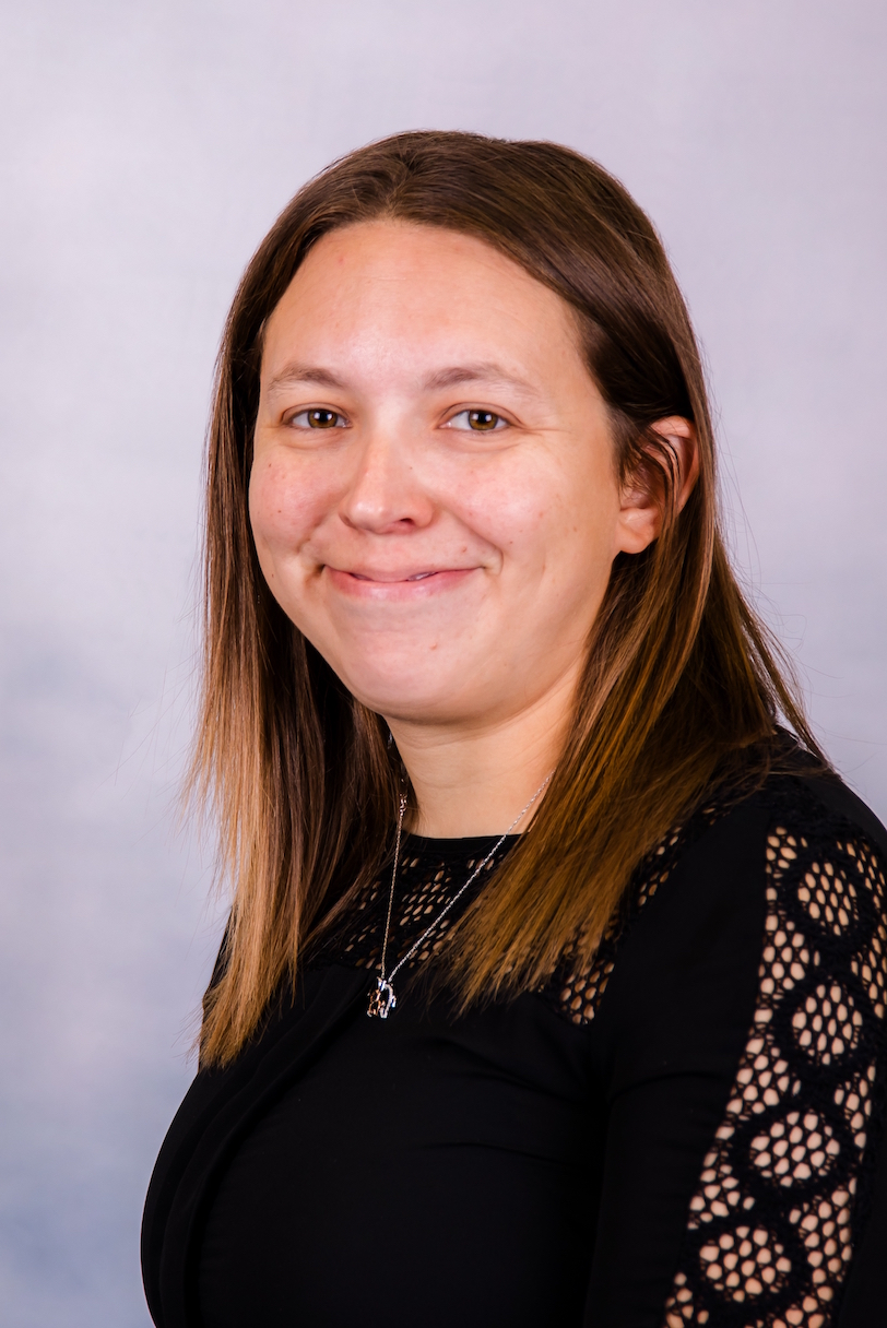 Portrait of a smiling person in a black top against a light gray background