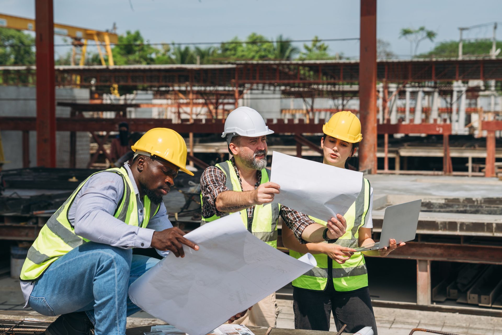Construction workers in hard hats reviewing blueprints at a building site
