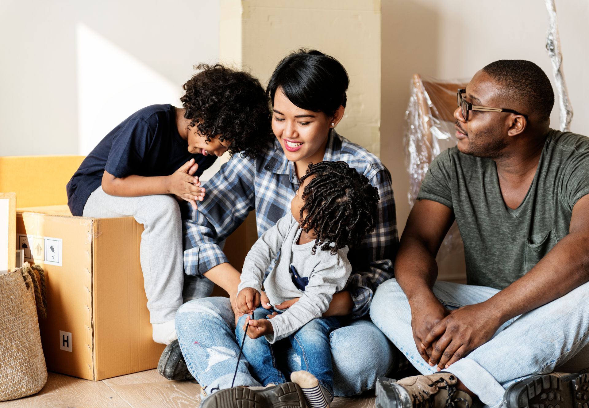 Family sitting together on a couch, smiling and embracing in a living room with moving boxes
