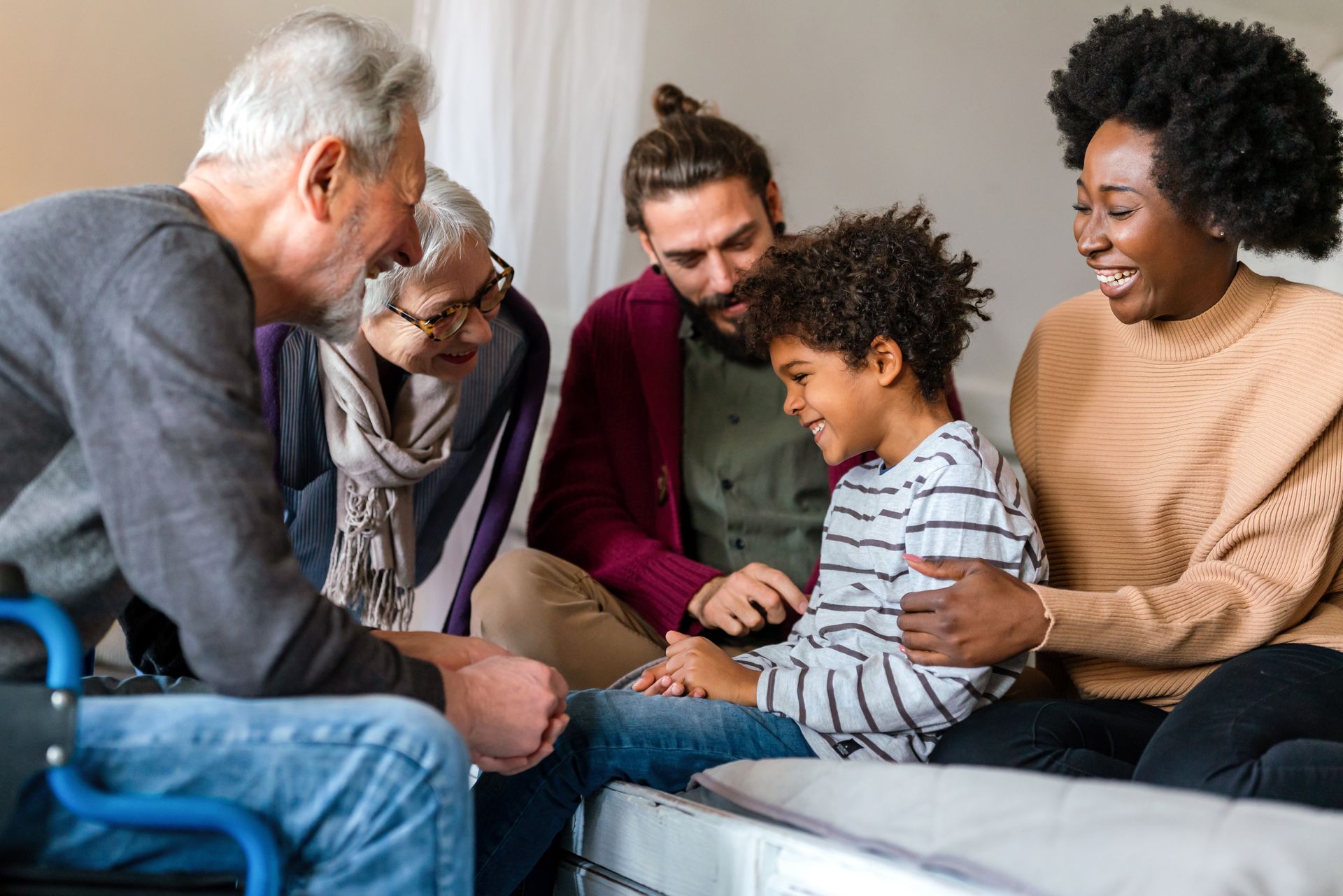 Family gathered on a couch, smiling and sharing a moment together in a cozy living room.