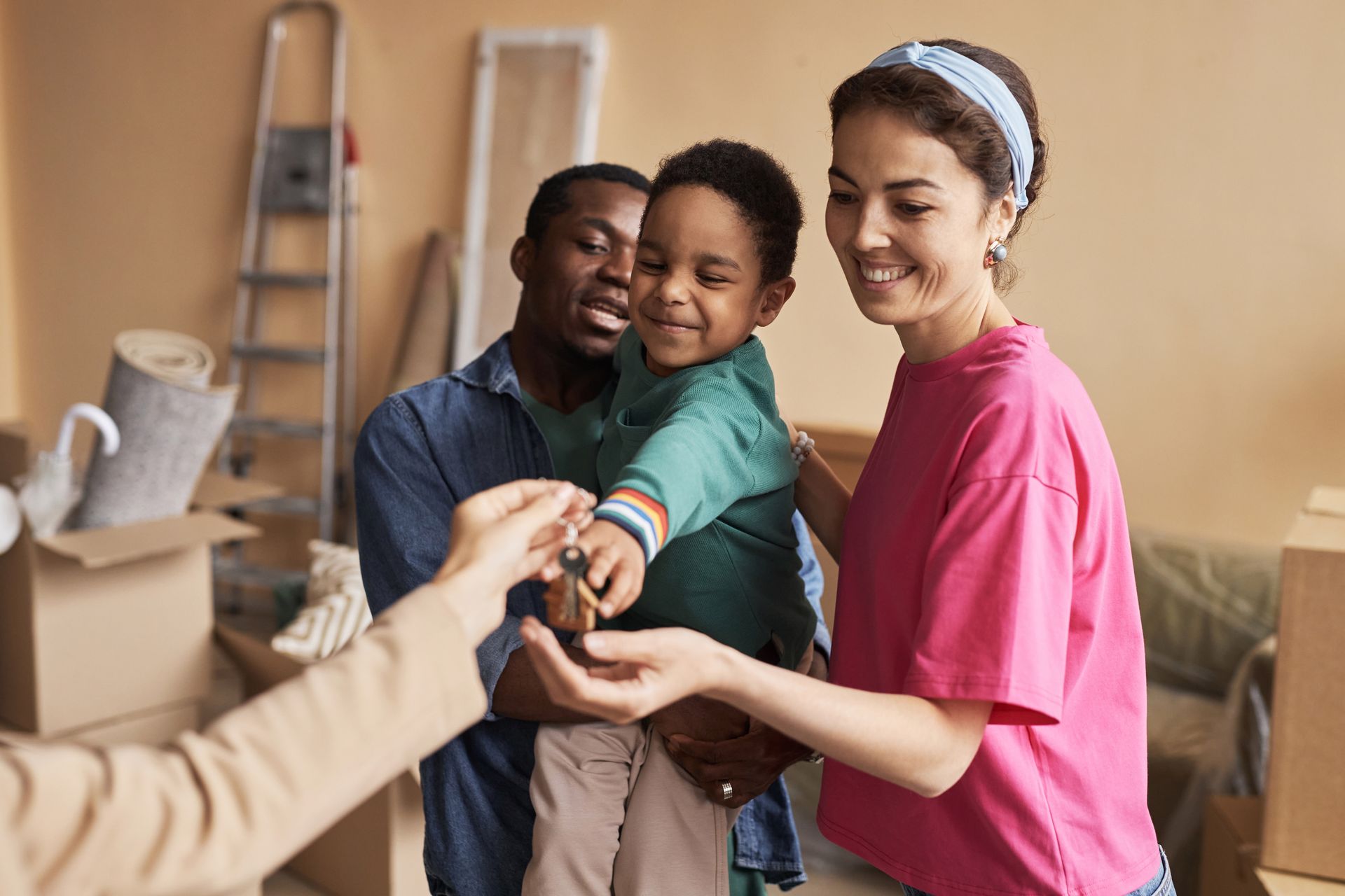 Volunteers handing supplies to a smiling family in a room with moving boxes