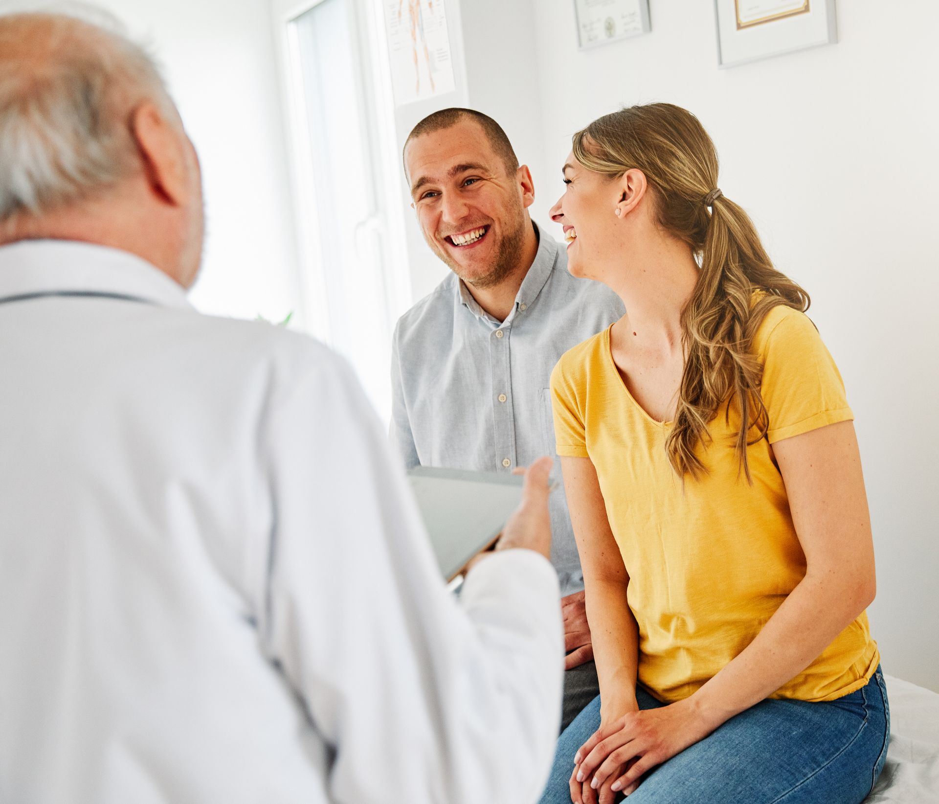 Doctor speaking with two smiling patients in a bright clinic room