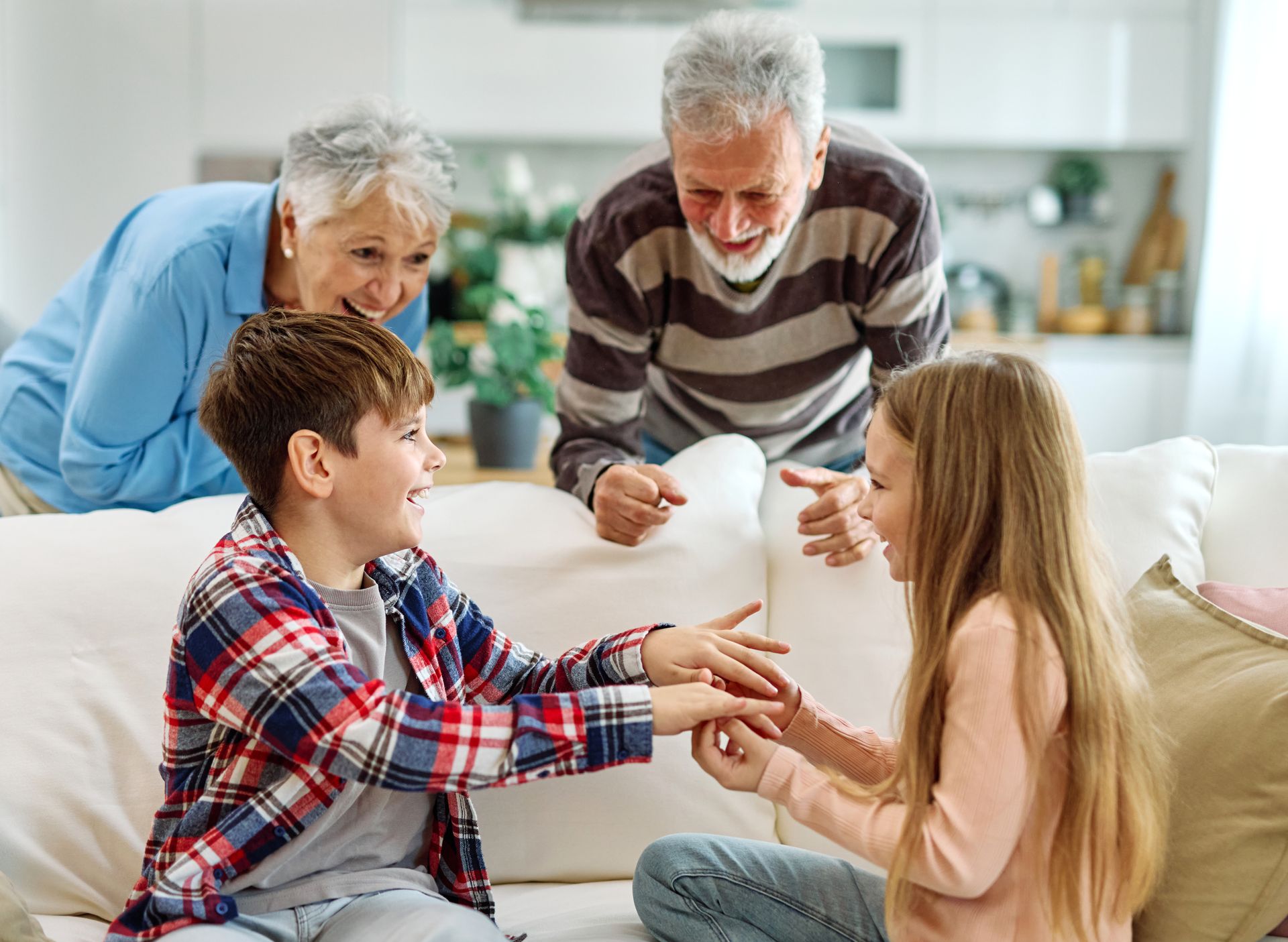 Family playing a hand-clapping game on a couch in a bright living room