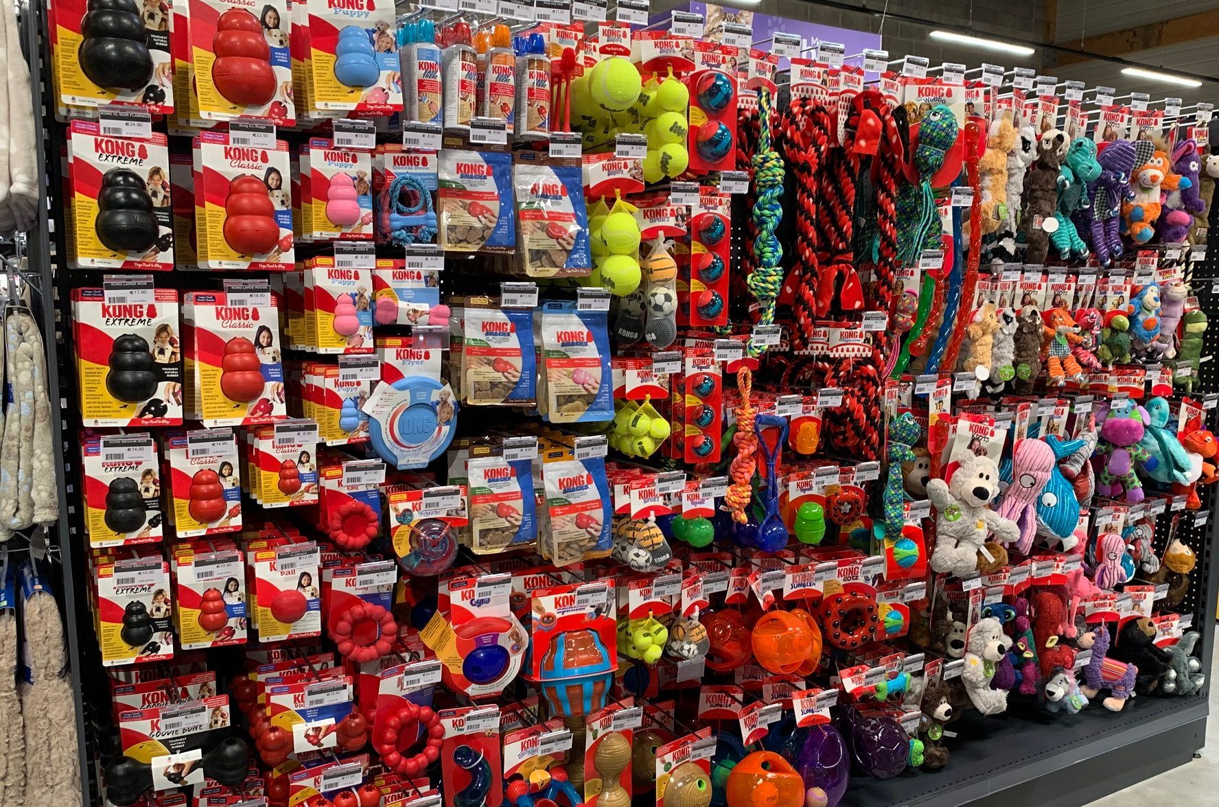 Un mur rempli de jouets pour chiens dans un magasin.
