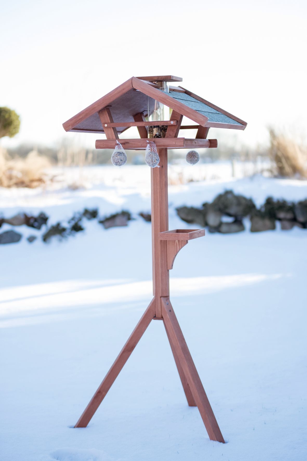 Une mangeoire à oiseaux en bois est posée dans la neige.