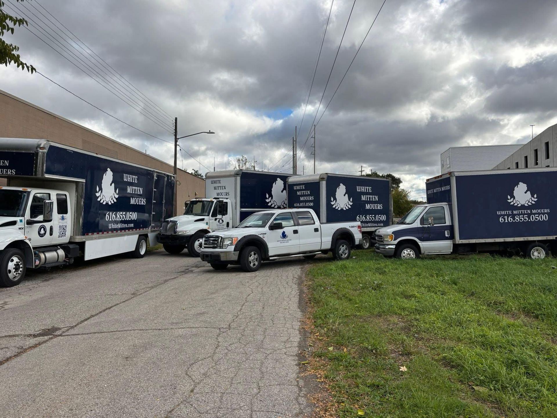 Fleet of white trucks with blue trailers parked in a lot under cloudy skies