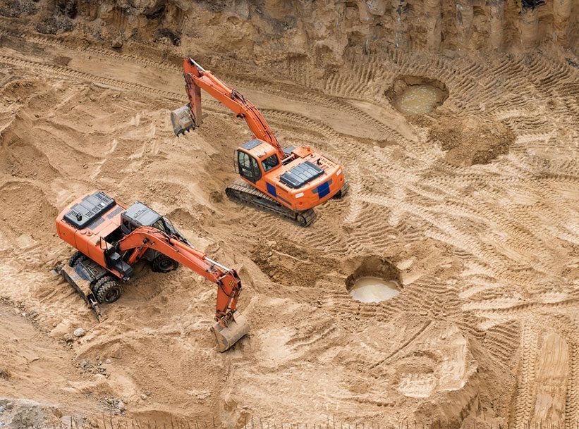 Two Excavators Are Working in A Dirt Field — Hillery Group in Bowen, QLD