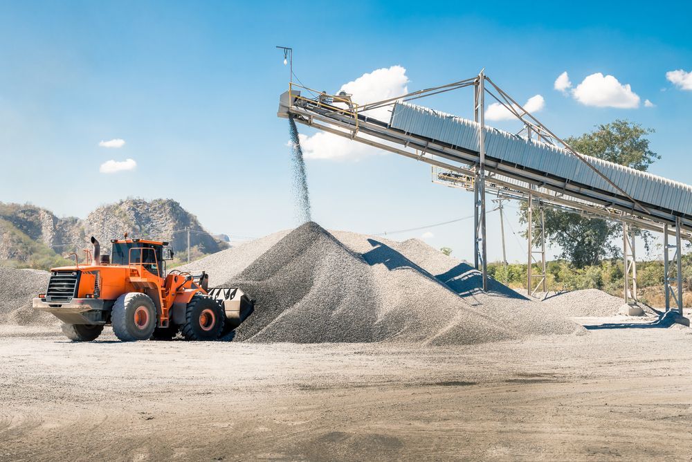 A Bulldozer is Loading Gravel Into a Conveyor Belt at a Construction Site — Hillery Group in Belmore, NSW