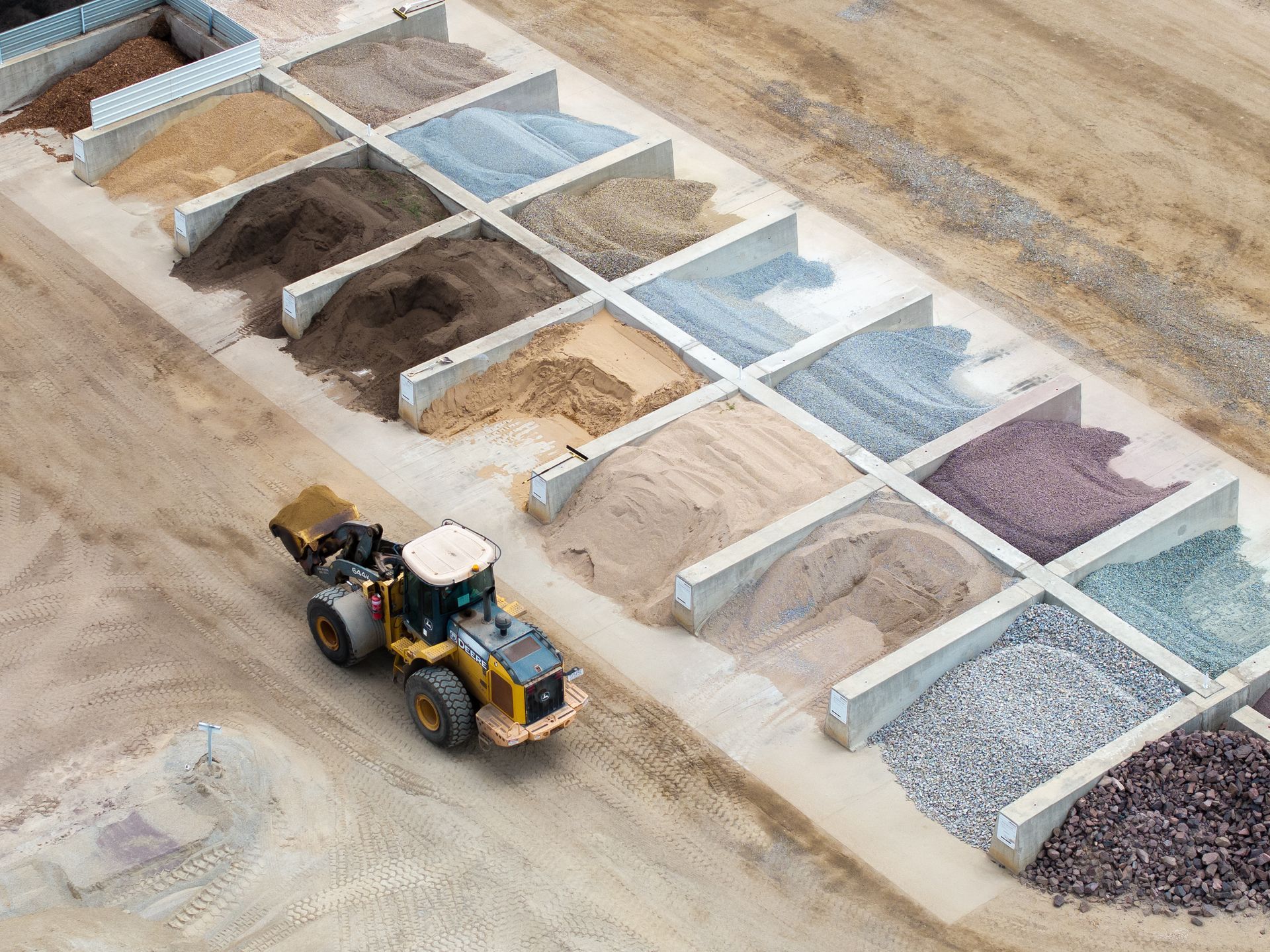 Construction Site With a Loader Beside Rows of Labeled Gravel, Sand, and Soil Piles — Hillery Group in Bowen, QLD