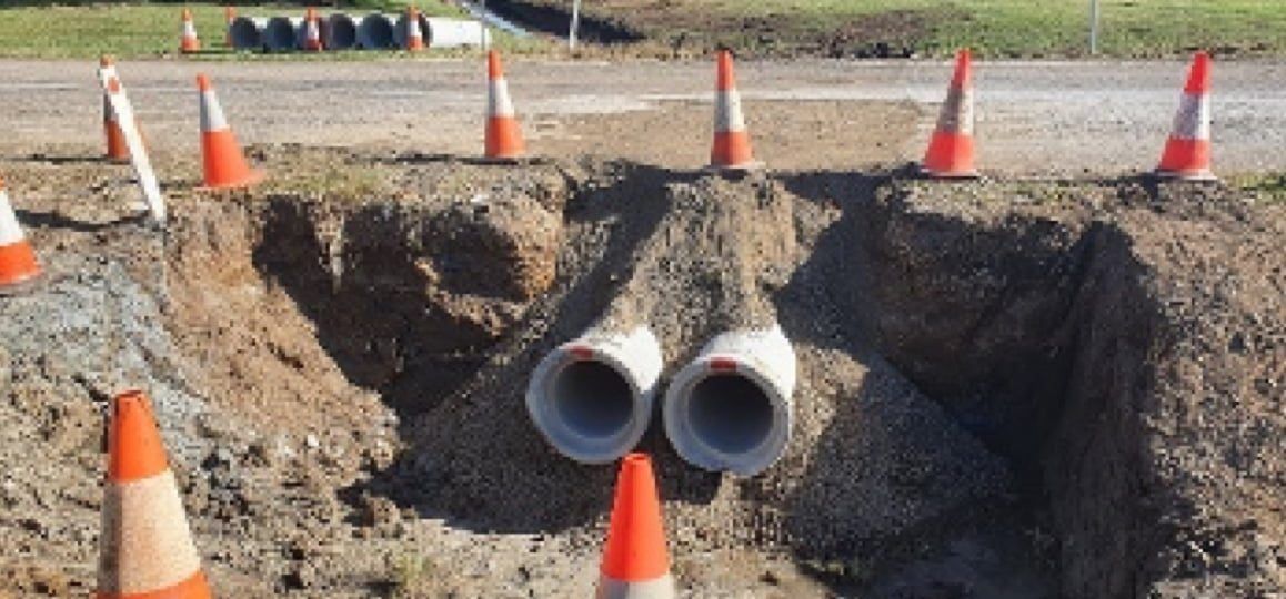 A Hole in The Ground with A Bunch of Traffic Cones in It — Hillery Group in Belmore, NSW