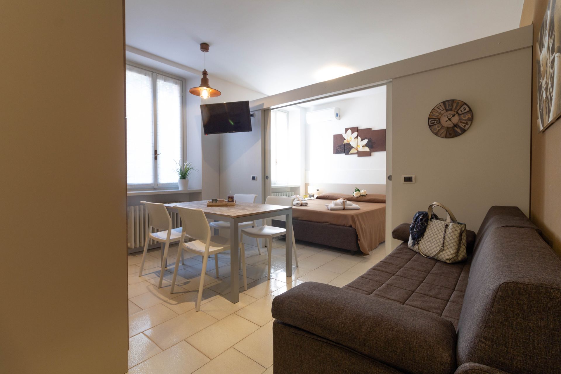 Luminoso appartamento con tavolo da pranzo, divano e zona letto in un ambiente compatto a pianta aperta.