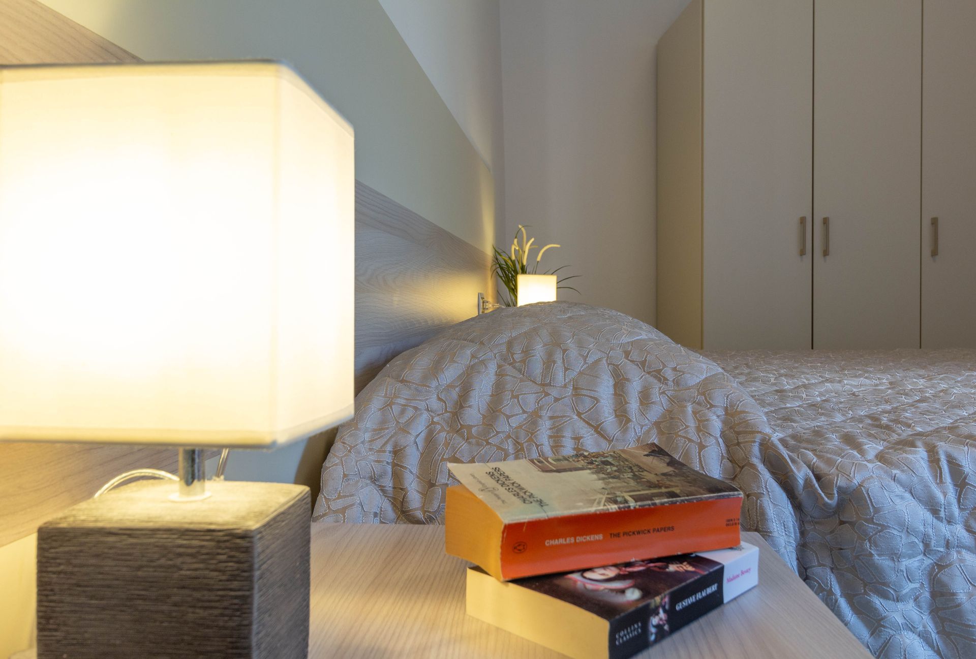 Tazze da caffè e una moka su un vassoio sopra un letto con una coperta rossa in una camera da letto.