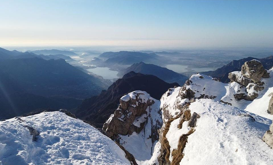 Cime montuose innevate che si stagliano su una valle lontana sotto un cielo azzurro e limpido.
