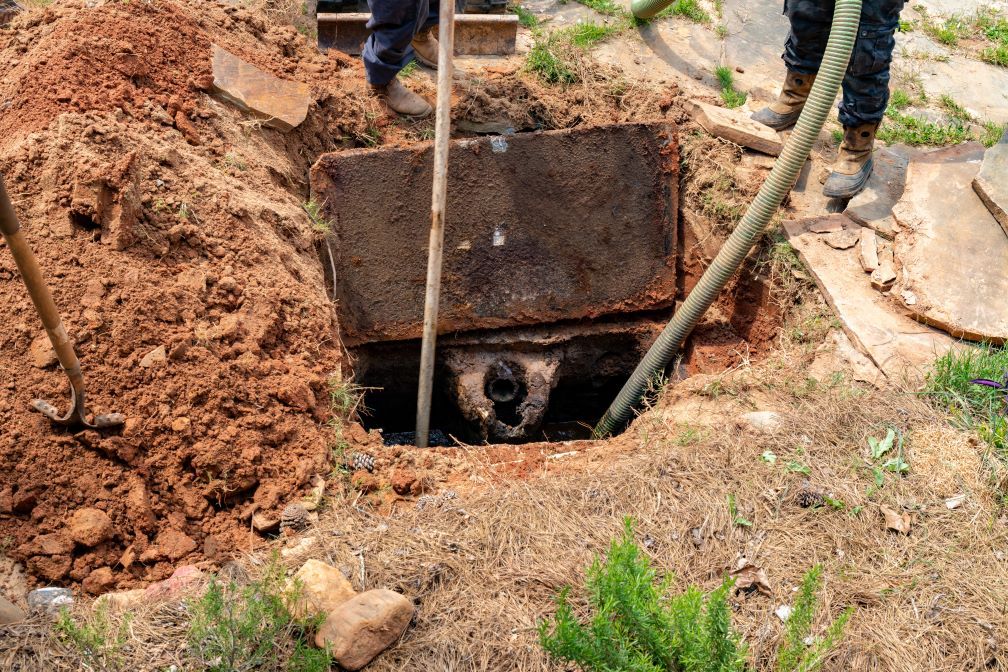 A man is digging a hole in the ground next to a manhole cover.