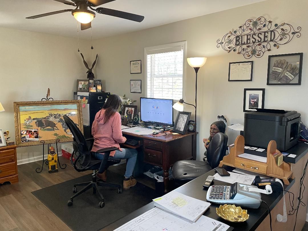 Woman working at a desk in a home office with another person in Lumberton, NC. 