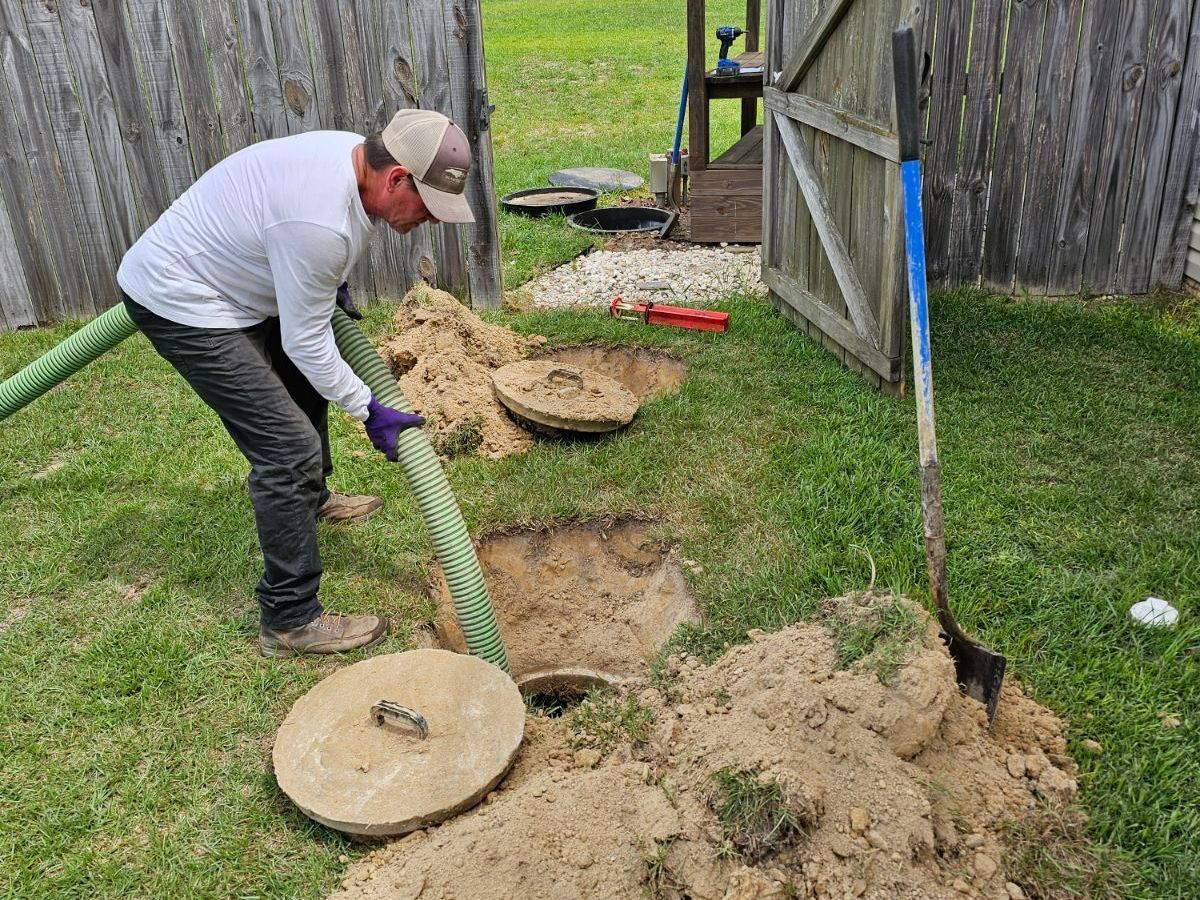 A man is cleaning a septic tank with a hose.