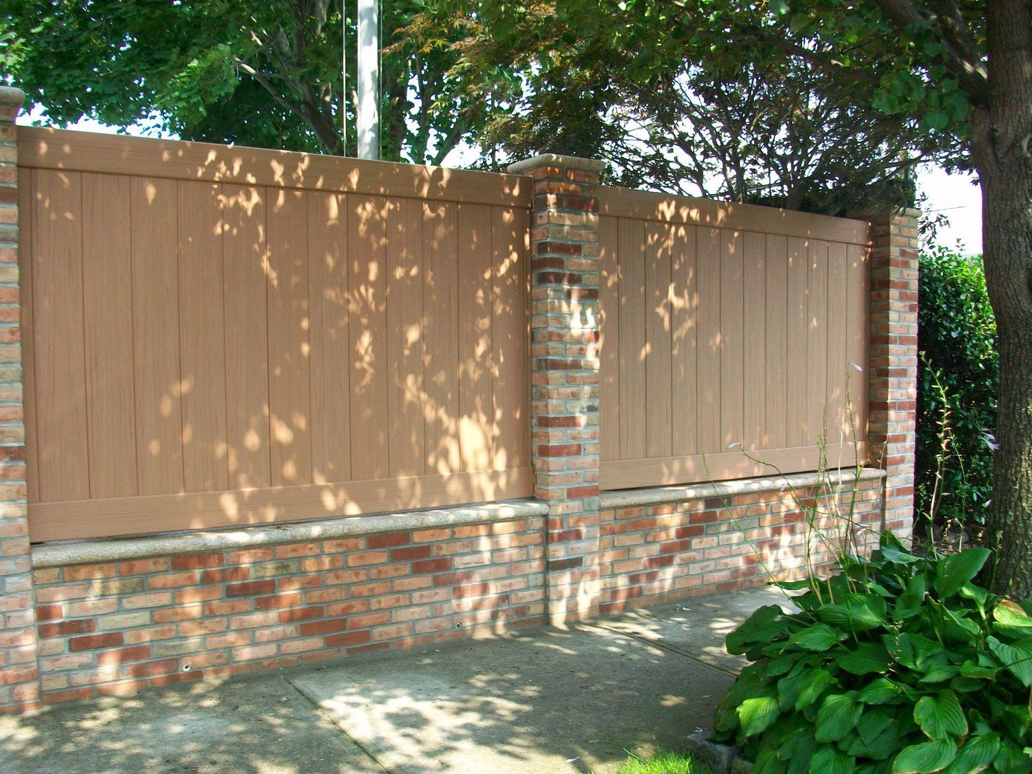 A brick wall with a wooden fence behind it