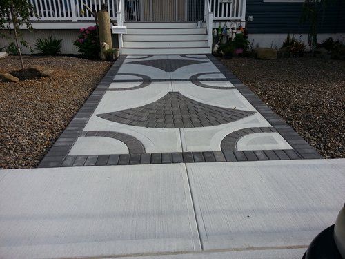 A brick walkway leading to a house with a design on it