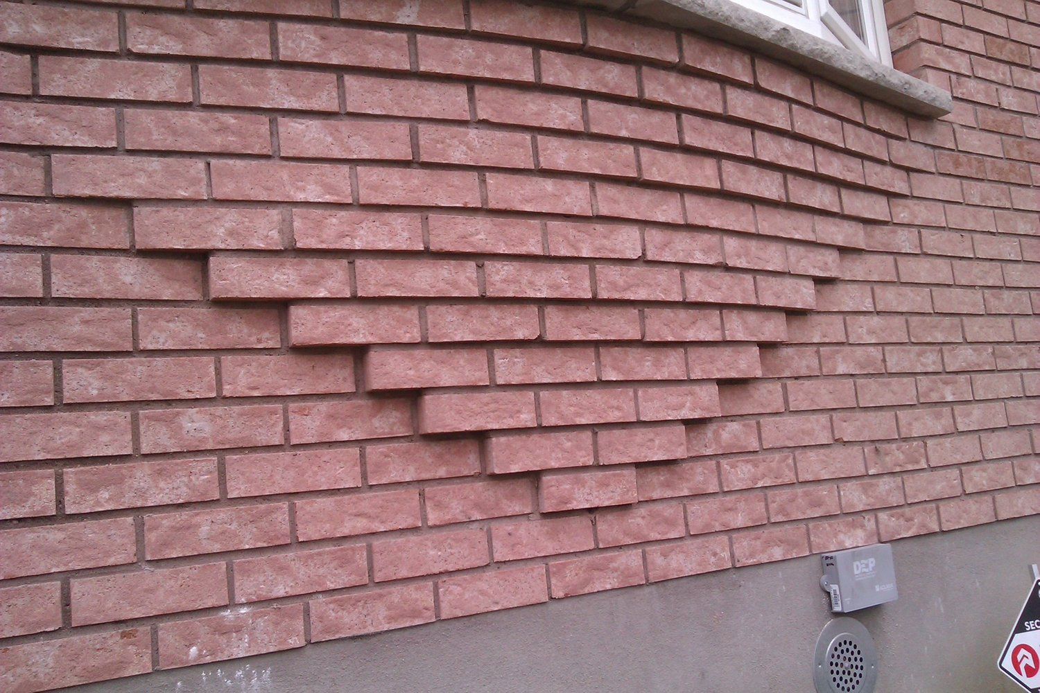 A brick wall with a no parking sign on it