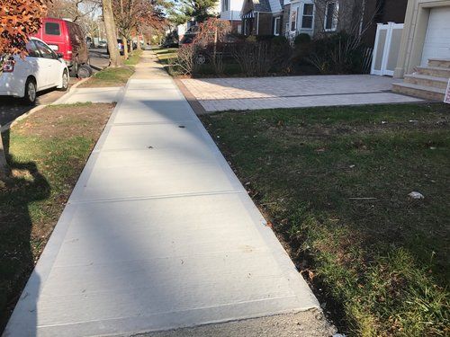 A concrete sidewalk leading to a house in a residential neighborhood.