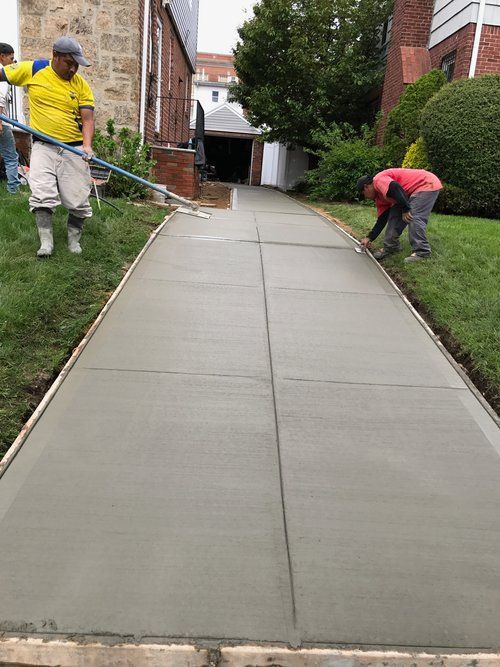 A couple of men are working on a concrete walkway.