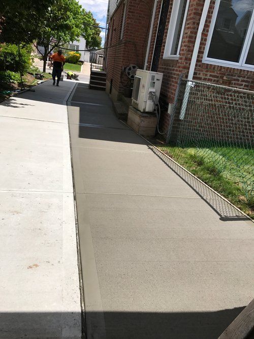 A person is walking down a sidewalk next to a brick building.