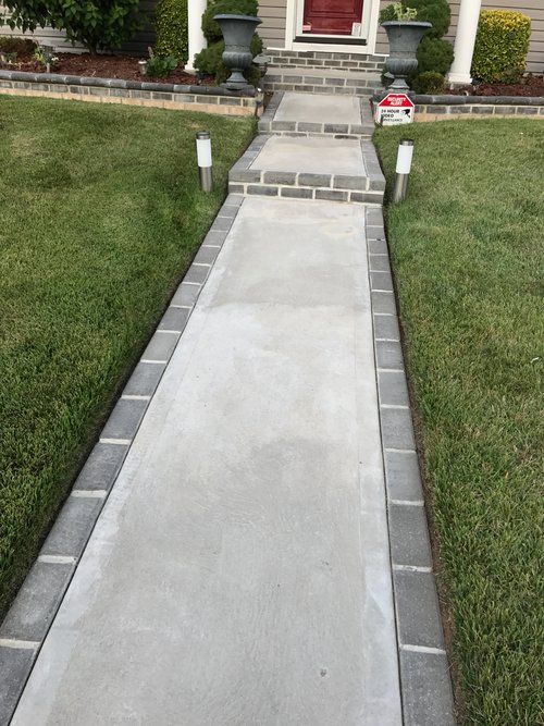 A concrete walkway leading to the front door of a house.