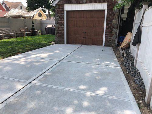 A concrete driveway leading to a garage with a brown door