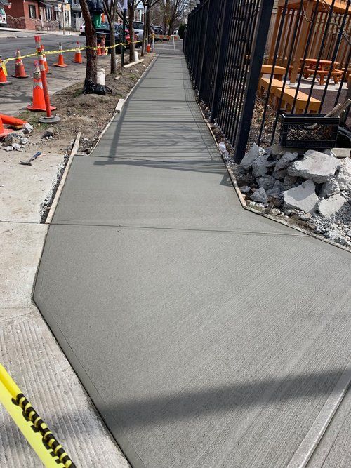 A concrete sidewalk is being built next to a fence.