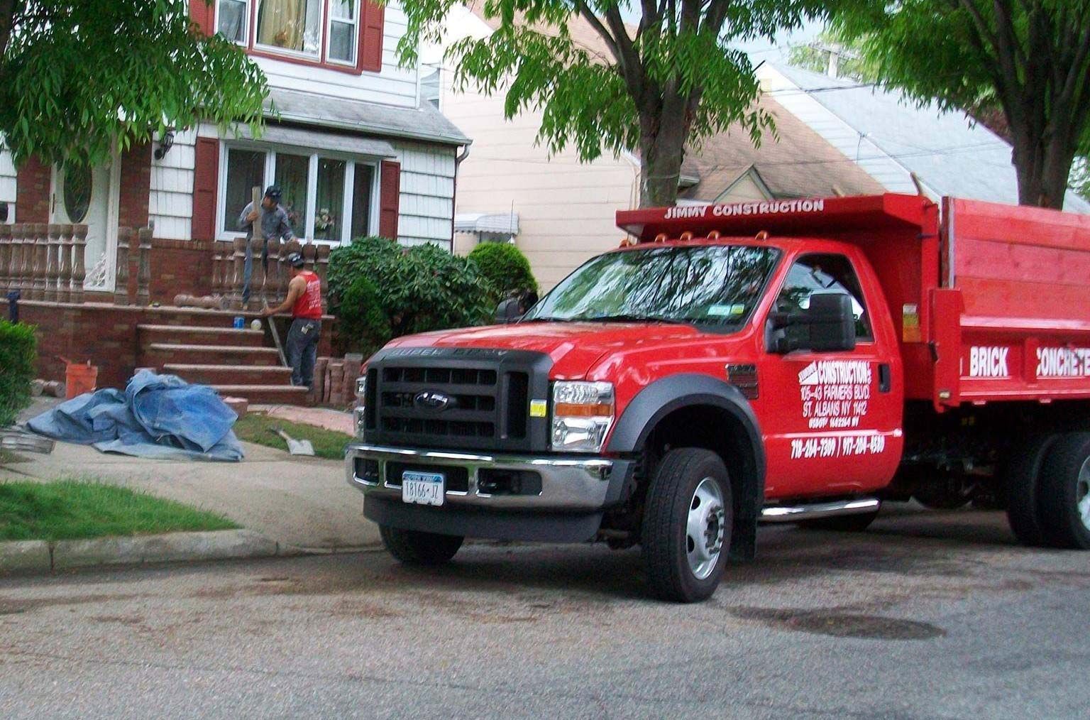 A red dump truck is parked in front of a house