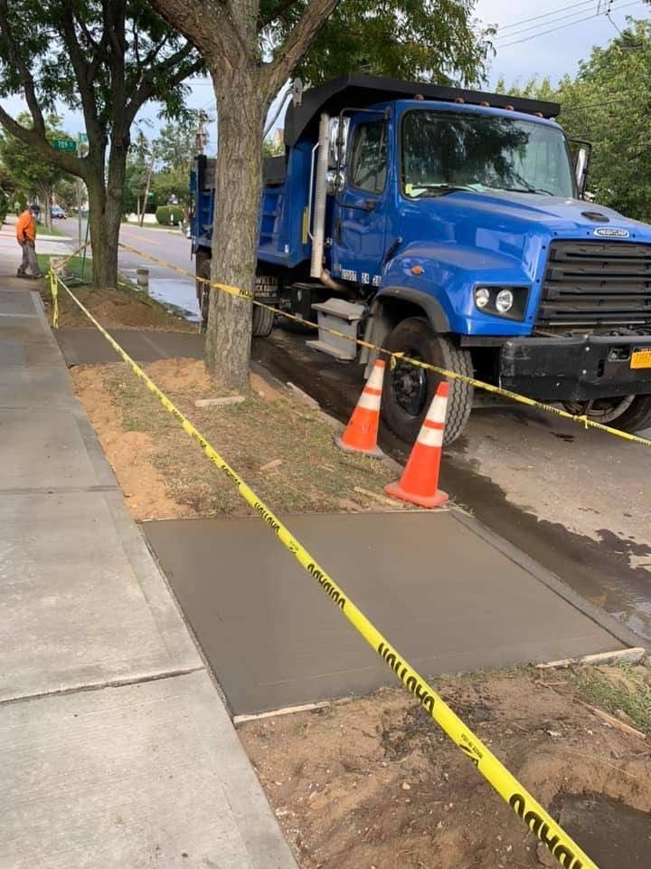 A blue dump truck is parked on the side of the road.