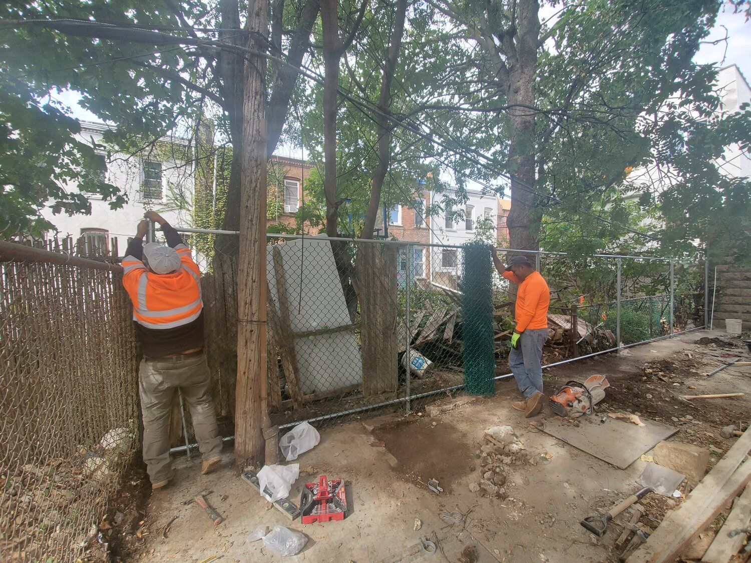 A couple of men are working on a chain link fence.