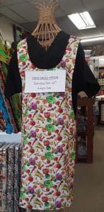 An apron with vegetables on it is hanging on a mannequin in a store.