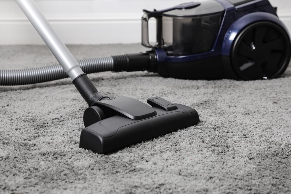 A vacuum cleaner is being used to clean a carpet.