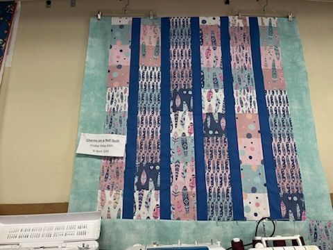 A quilt with rabbits on it is hanging on a wall.