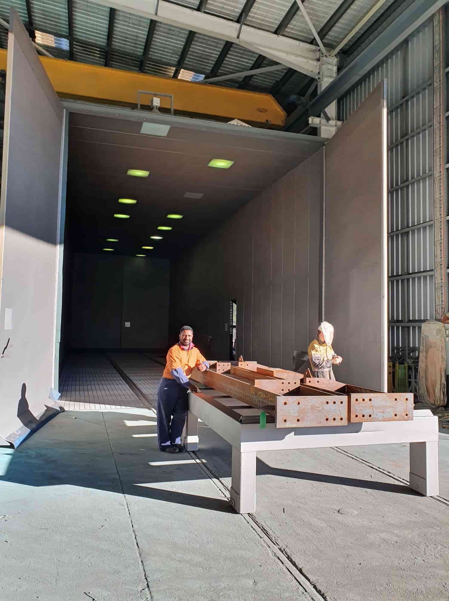 Person Using a Roller to Apply Dark Blue Coating — Waters Abrasive Blasting Services In Cardwell, QLD