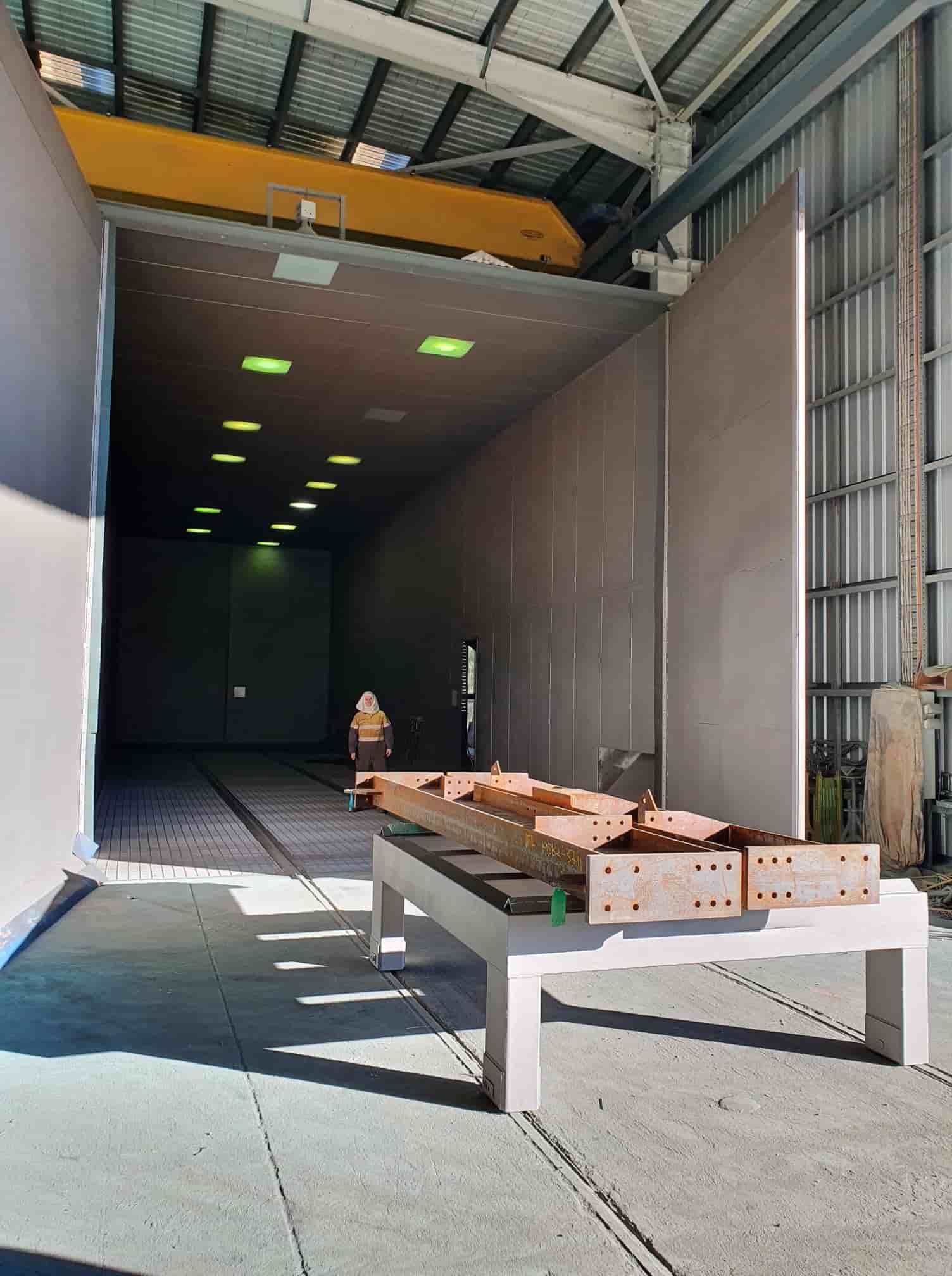 A Large Warehouse With a Crane in the Background — Waters Abrasive Blasting Services In Shaw, QLD