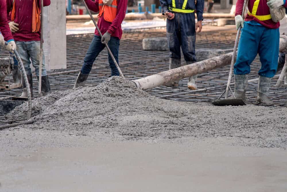 A Group of Construction Workers Are Working on a Concrete Floor — Waters Abrasive Blasting Services In Shaw, QLD