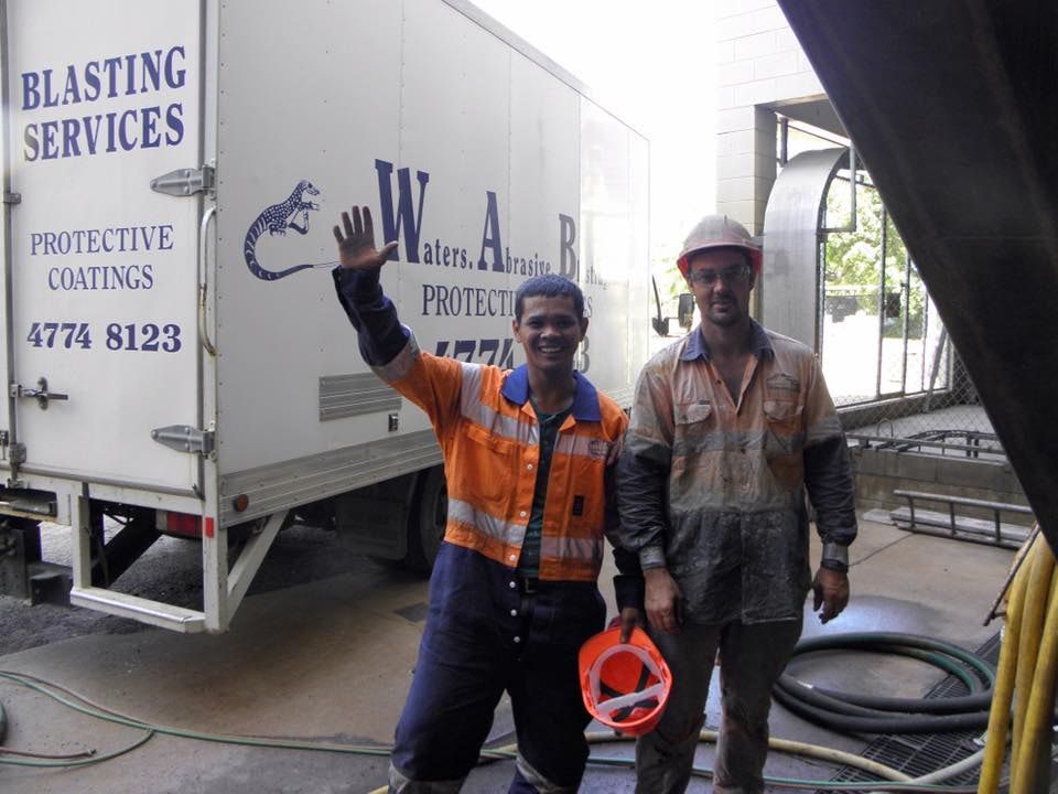 Hand Using a Trowel to Apply Drywall Mud on a Wall — Waters Abrasive Blasting Services In Gladstone, QLD